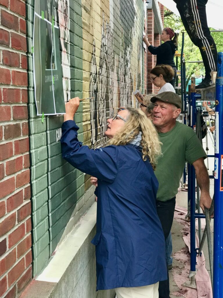 hangouts-Keene-19--David-Goldstein--Deryn-Graieg-painting-on-Faulkner-mural-e1566141565512-768x1024.jpg